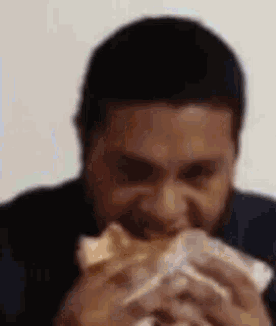 a man with a beard is eating a sandwich with his mouth open .