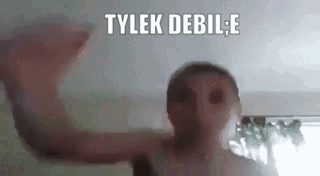 a man without a shirt is standing in front of a wall with the words tylek debile written on it