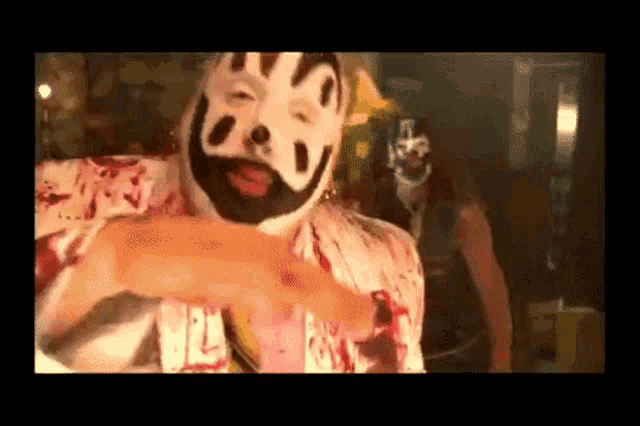 a man in a clown costume is pointing at another man in a mask .