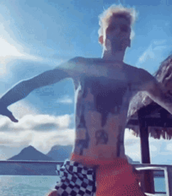 a shirtless man with a tattoo on his chest is standing on a boat .