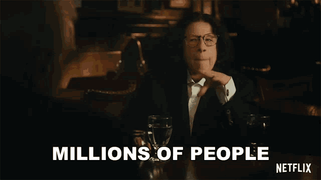 a man in a suit and tie is sitting at a table with a glass of water and says millions of people netflix