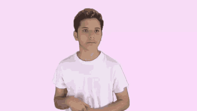 a young man is wearing a white t-shirt and making a funny face .
