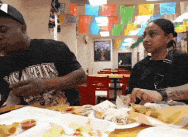 a man wearing a los angeles t-shirt sits at a table with a woman