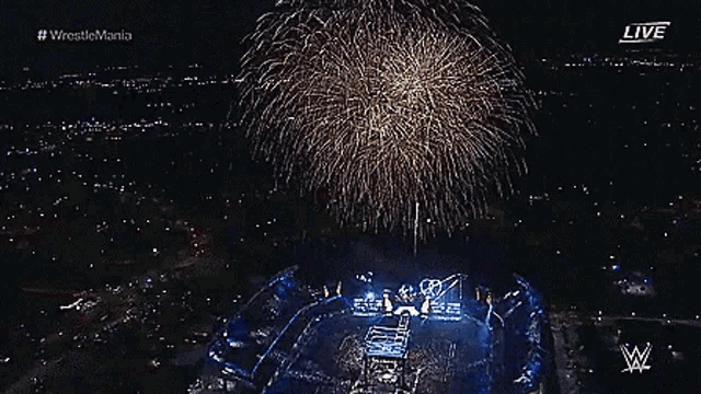 a woman in a green outfit stands in front of a fireworks display during a live wrestlemania event