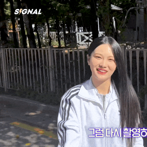 a woman in a white adidas jacket smiles in front of a fence