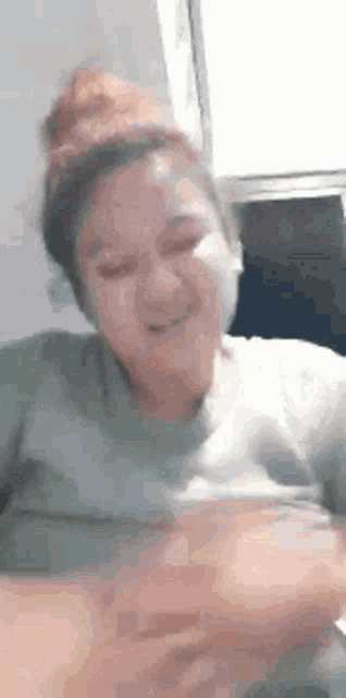 a woman in a green shirt is sitting at a table with her eyes closed and smiling .