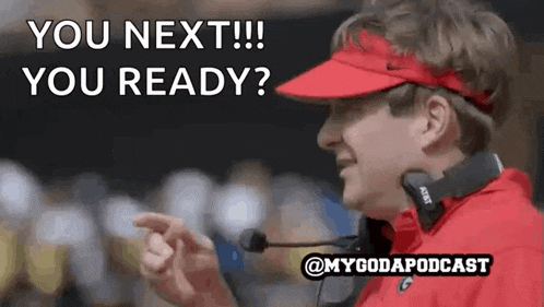 a man wearing a red visor and headphones is talking into a microphone .