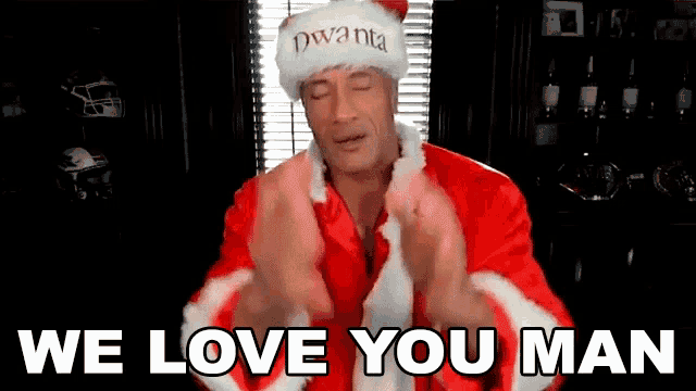 a man in a santa suit is saying we love you man with his hands in the air .