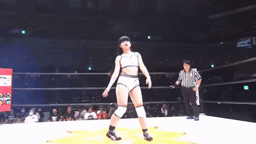 a woman is standing in a ring with a green exit sign in the background