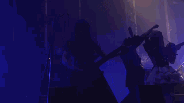 a man is playing a bass guitar in front of a drummer