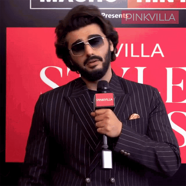 a man in a suit is holding a microphone that says pinkvilla on it