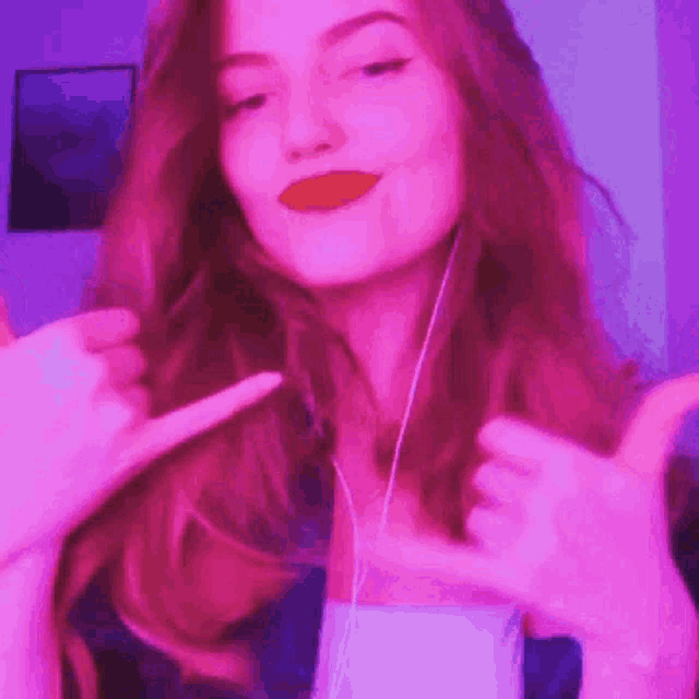 a woman with long red hair is wearing headphones and making a funny face .