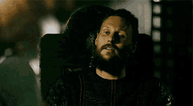 a man with a beard is sitting with his eyes closed in a chair .
