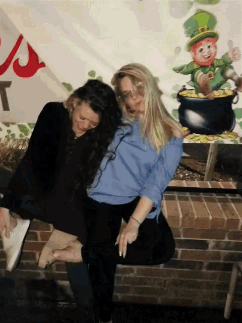 two women are posing for a picture in front of a leprechaun