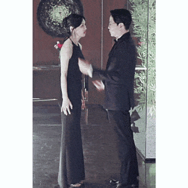 a woman in a black dress stands next to a man in a black suit