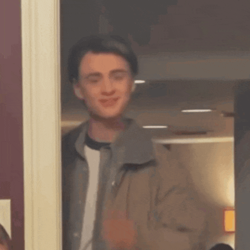 a man is standing in front of a door blowing a kiss .