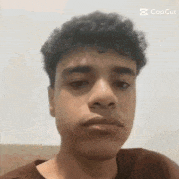 a young man with curly hair is making a funny face while looking at the camera .