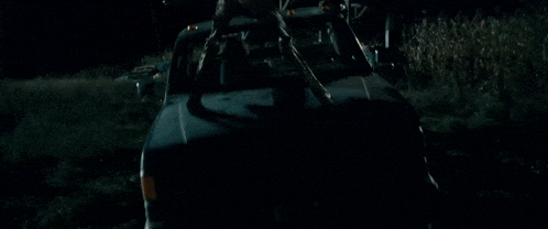 a man is driving a truck in a field at night