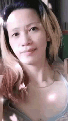 a close up of a woman 's face with long hair and a necklace .