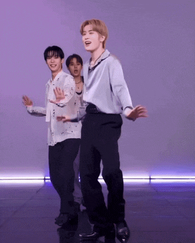 three young men are dancing together on a stage in front of a purple background .