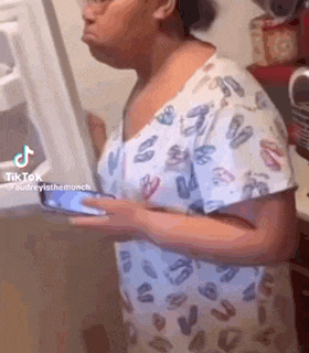 a woman is standing in front of a refrigerator and holding a cell phone .