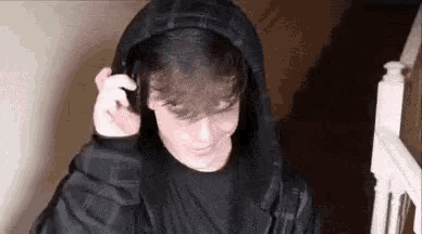 a young man wearing a black hoodie and headphones is standing on stairs .