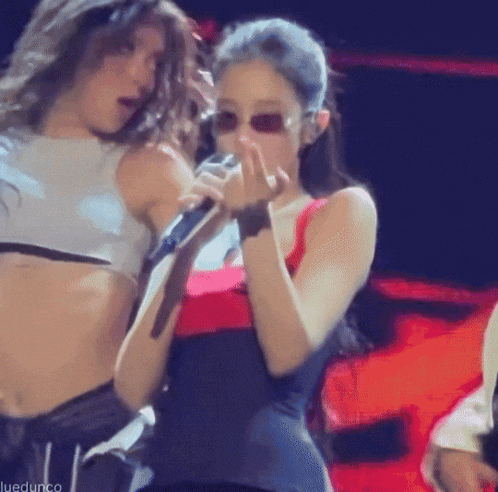 a woman is singing into a microphone while wearing sunglasses