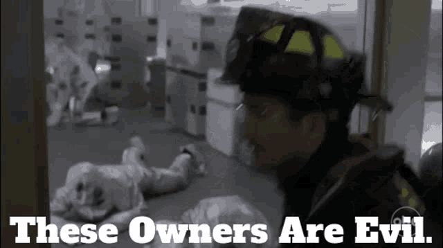 a fireman is standing in a room with the words these owners are evil above him