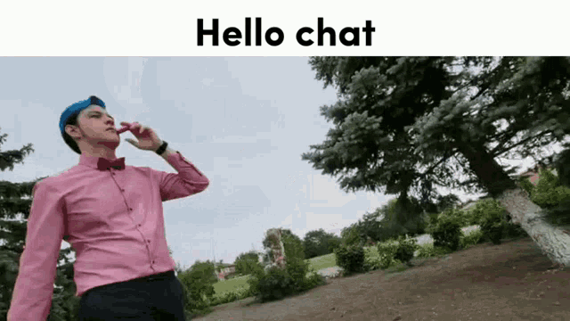 a man in a pink shirt and blue hat is talking on a cell phone with the words hello chat above him