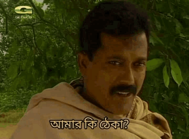 a man with a mustache is standing in front of a tree with a foreign language on his face .
