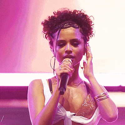 a woman is singing into a microphone with a purple background