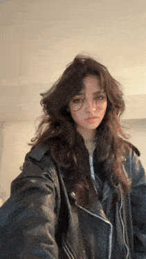 a girl with long hair is wearing a leather jacket