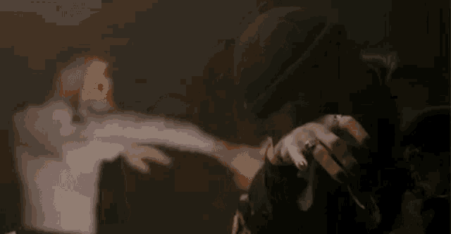 a man in a mask is holding a microphone in a dark room while another man holds a gun .