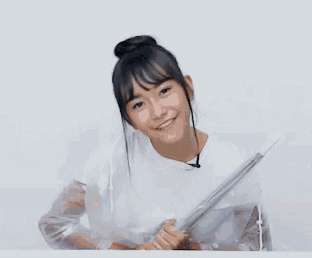 a girl in a white shirt is smiling while holding a clear umbrella