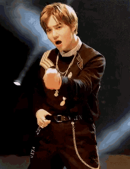 a young man wearing a black sweater and black pants is pointing his finger