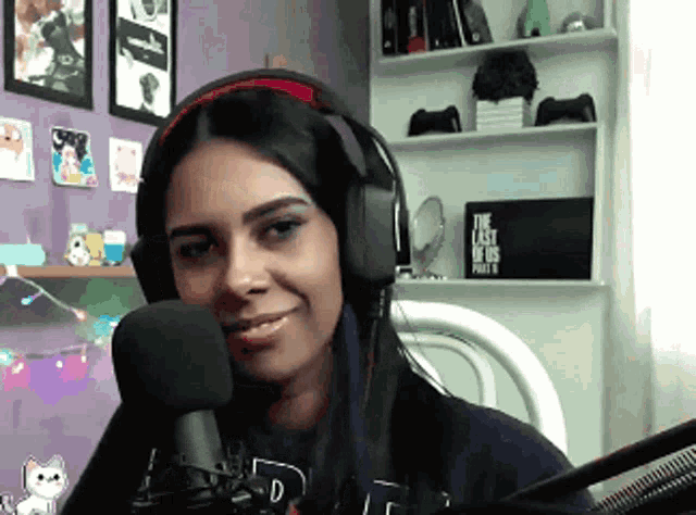 a woman wearing headphones is smiling in front of a microphone with a sign that says the last of us part ii