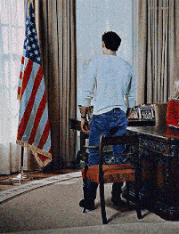 a man is standing in front of an american flag in a room