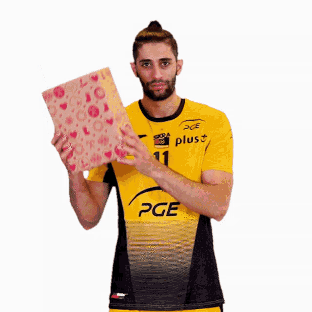 a man wearing a yellow pge shirt holds a gift box