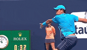 a man in a blue shirt is swinging a tennis racket at a tennis ball
