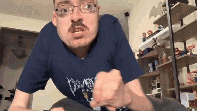 a man with glasses and a mustache wearing a blue shirt that says disarray