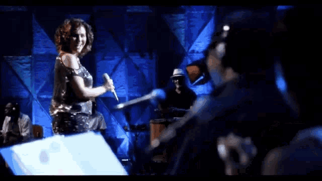 a woman in a silver dress is dancing on a stage in front of a crowd