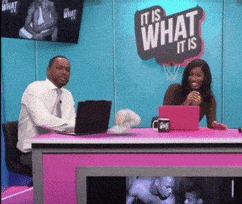 a man and a woman are sitting at a pink table with a sign that says it is what it is