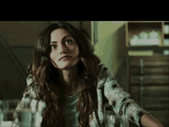 a woman with long hair is sitting at a table looking up