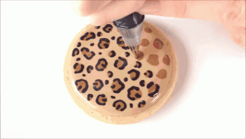 a person is decorating a cookie with a leopard print design