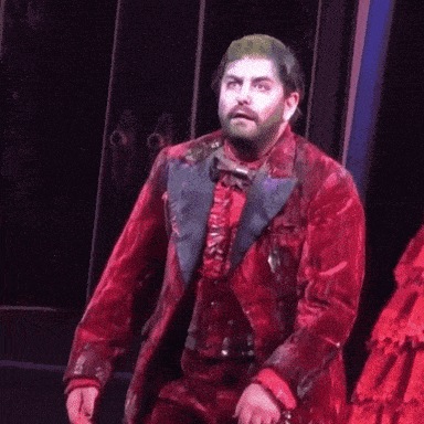 a man with a beard is wearing a red suit and a blue bow tie .