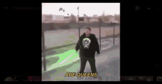 a man in a black shirt is holding a green light saber and says are queens lady gaga