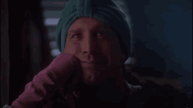 a man wearing a green turban and a pink glove looks at the camera