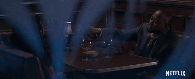 a man in a suit is sitting at a table with a netflix logo behind him