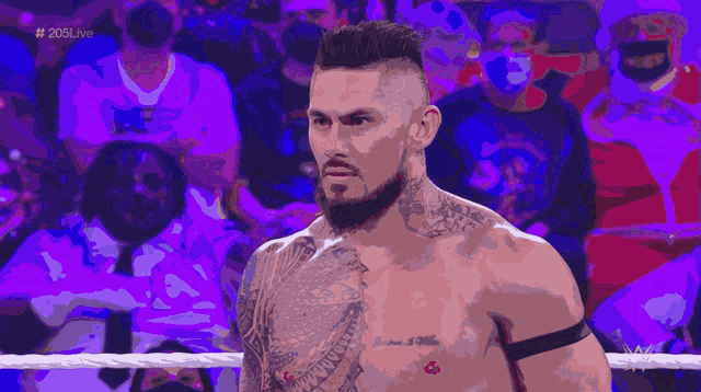a man with a tattoo on his chest stands in a wrestling ring with the hashtag # 205live