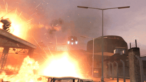 a car is on fire in front of a building with a tower in the background